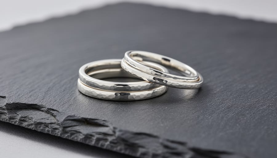 Stacked artisan silver rings arranged on slate stone and linen fabric.